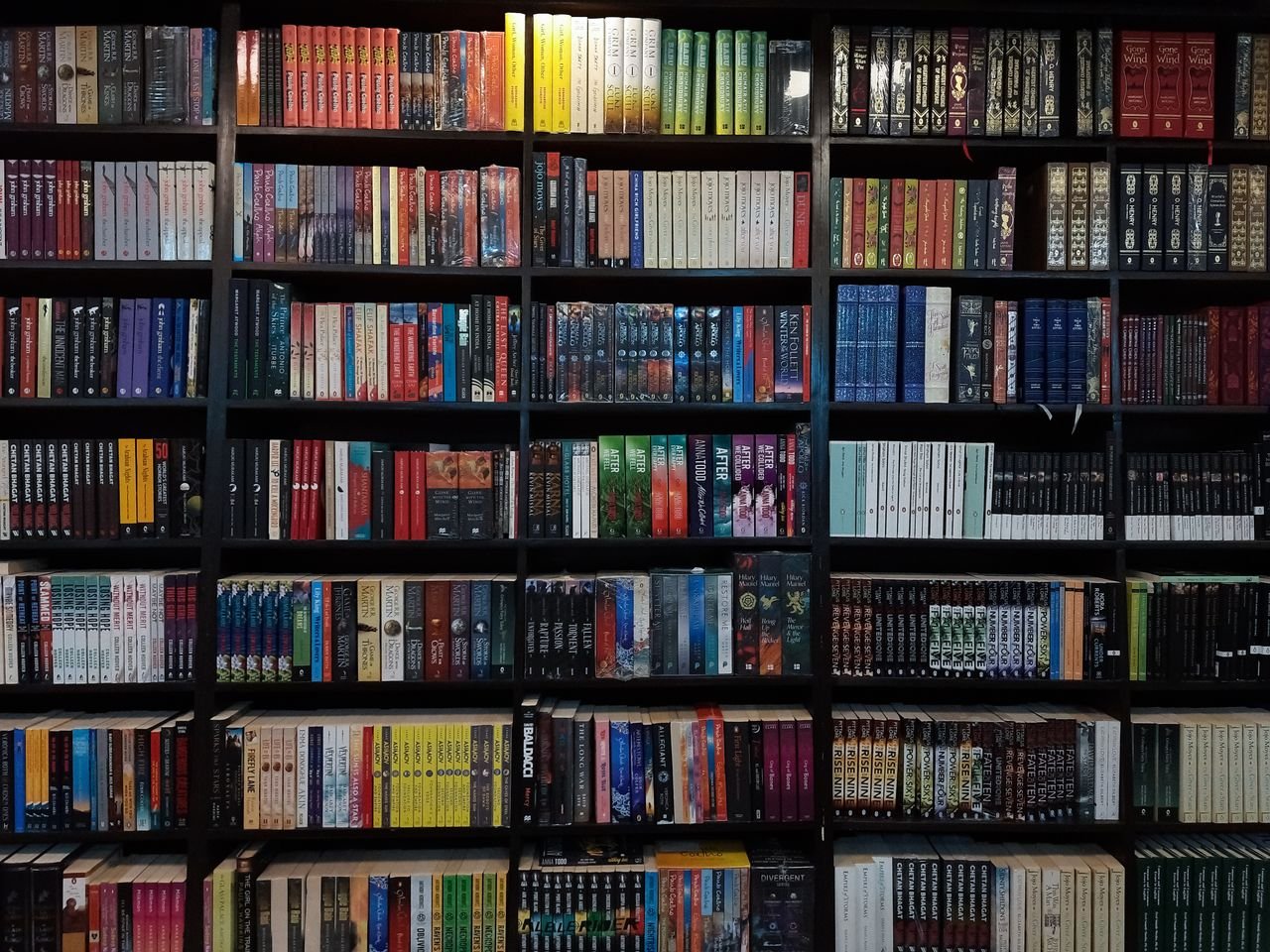 our-services-1 Diverse collection of books on a library shelf in Dhaka, Bangladesh.