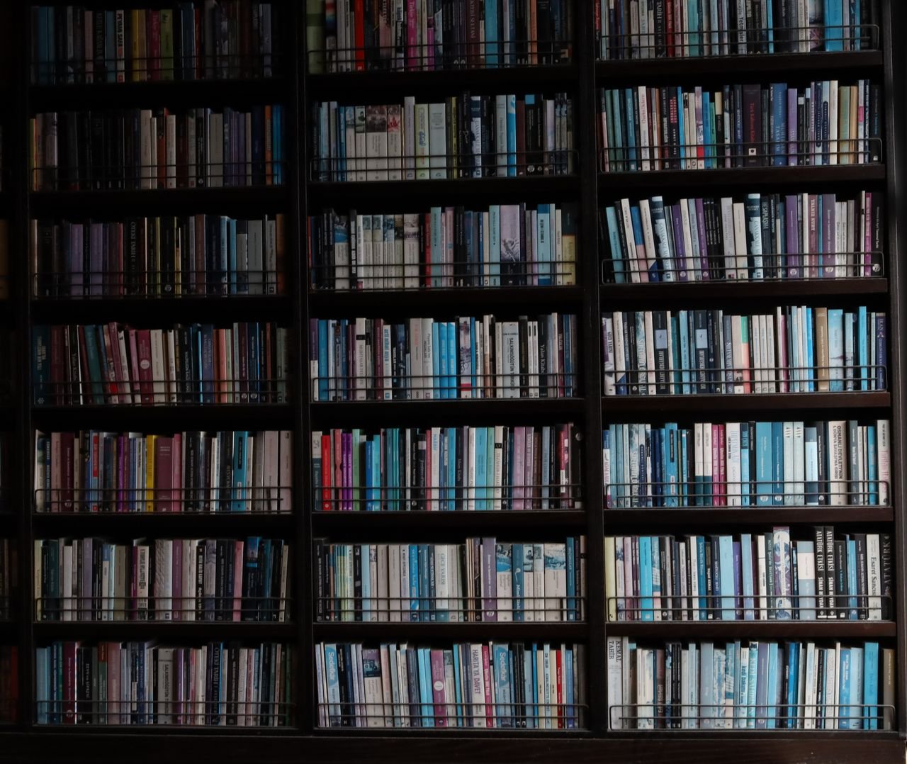 Bookshelf filled with a variety of colorful books indoors, showcasing diversity in book arrangement.